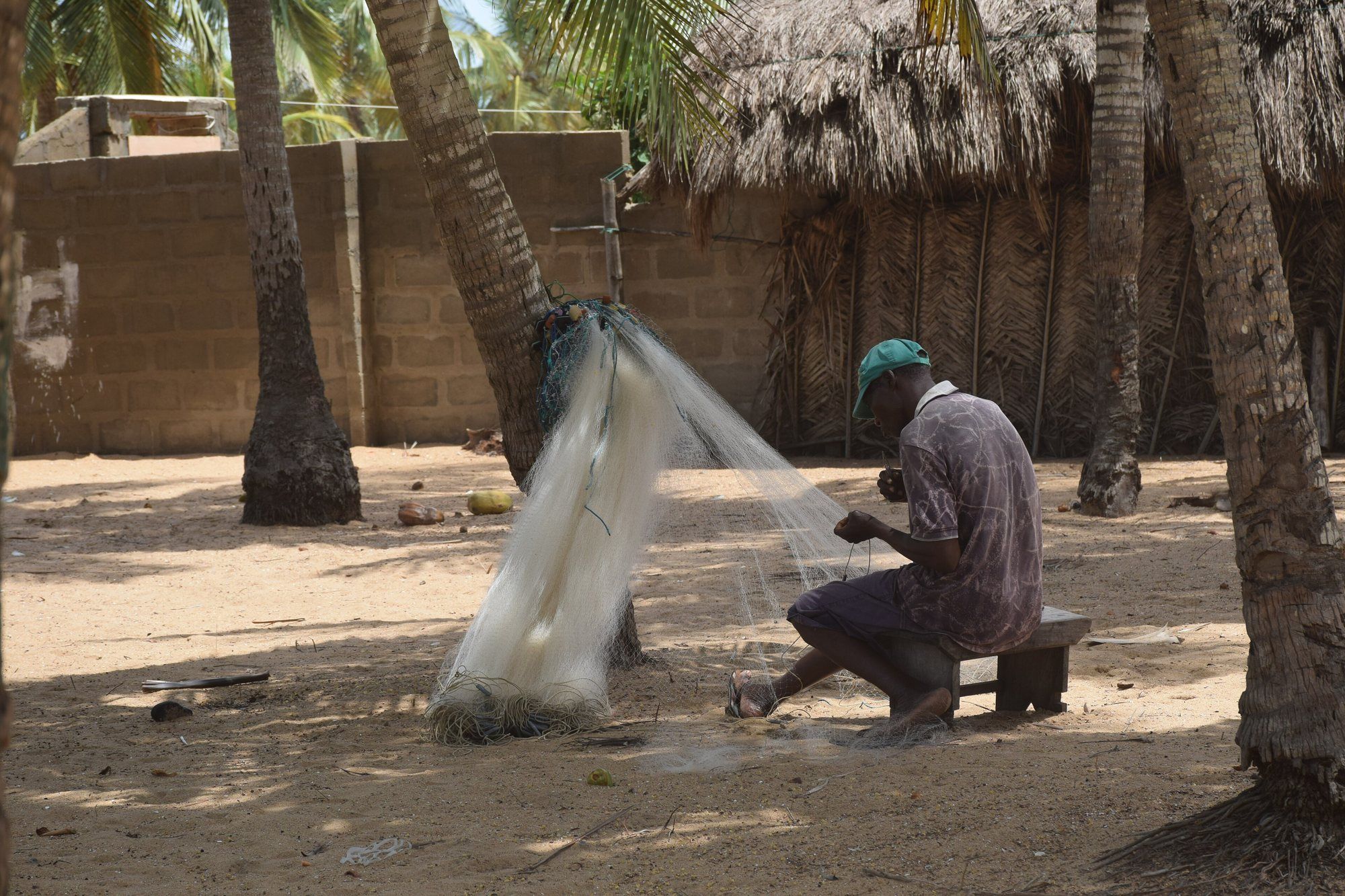 Un artisan tisse un filet de pêche à l’ombre des cocotiers, à Grand-Popo au Bénin.