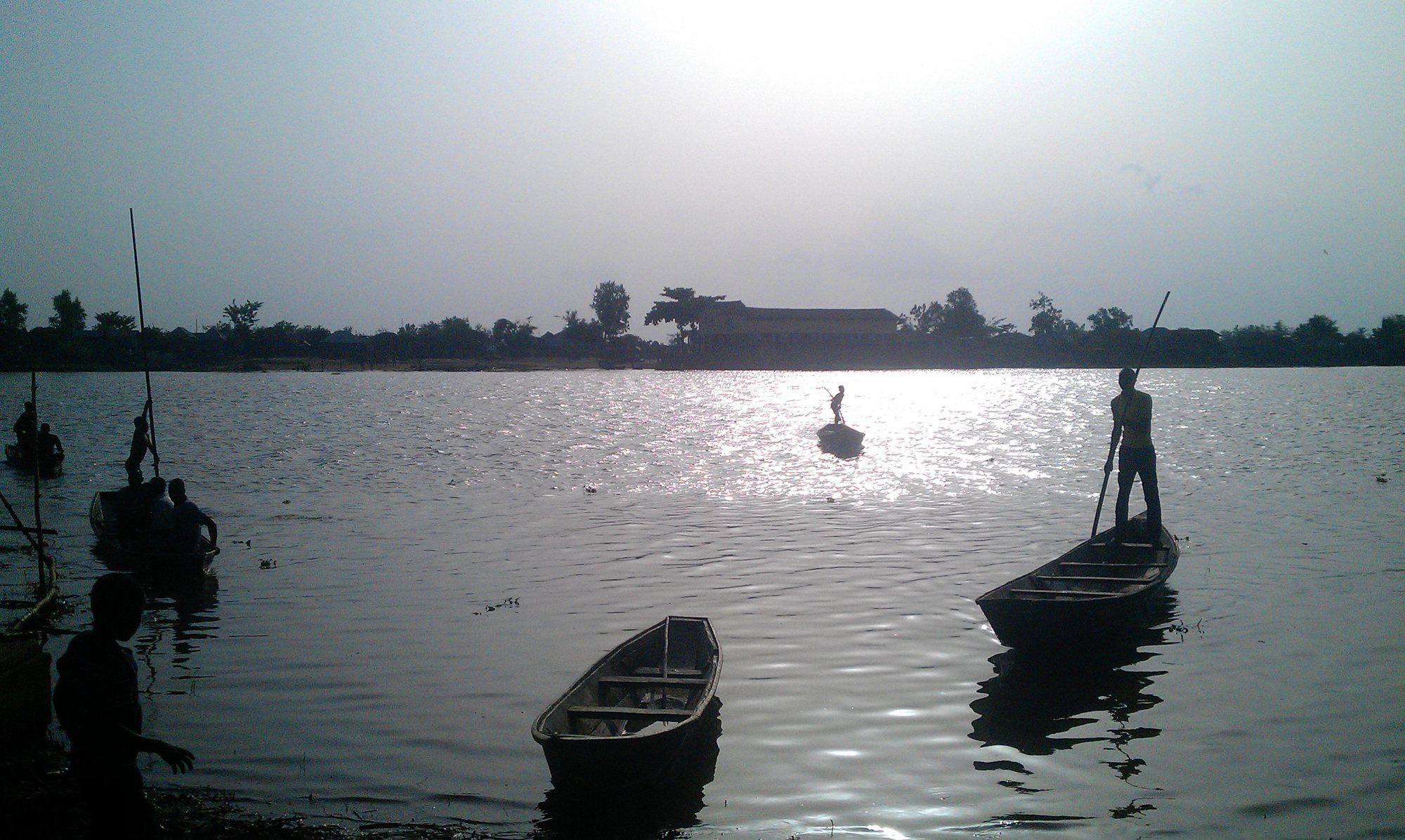 Des pêcheurs debout sur leurs pirogues glissent sur le fleuve Ouémé, à Hêtin-Sota, au Bénin.